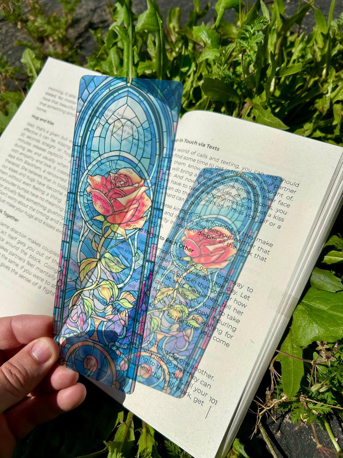 May include: Two stained glass bookmarks with a rose design. The bookmarks are translucent and feature a blue, pink, and green color scheme. The text on the bookmarks reads "Say Good Things to Each Other" and "In Touch via Texts".